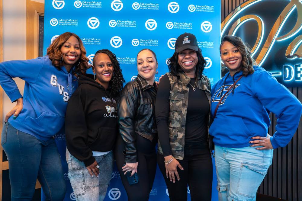 Group of five event attendees posing for photo in front of GV back drop